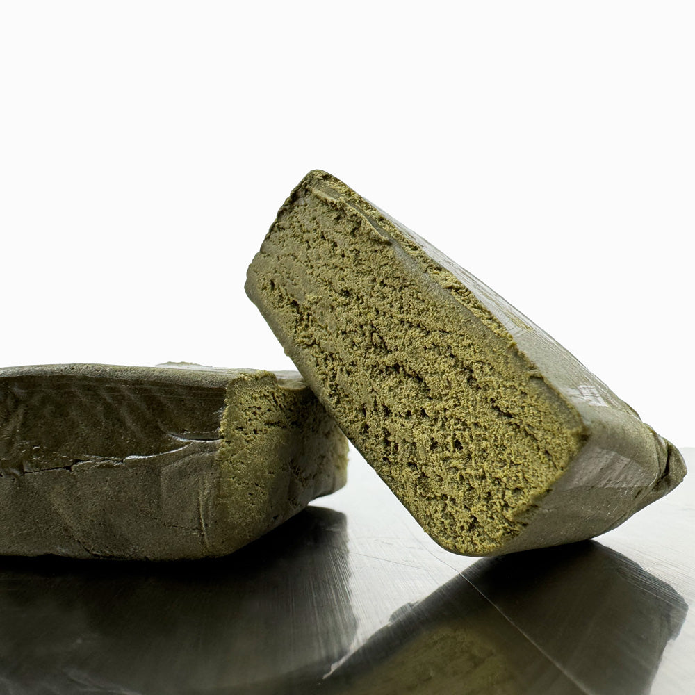 Zoom sur un morceau de CBD Bubble Hash coupé en deux posé sur une table