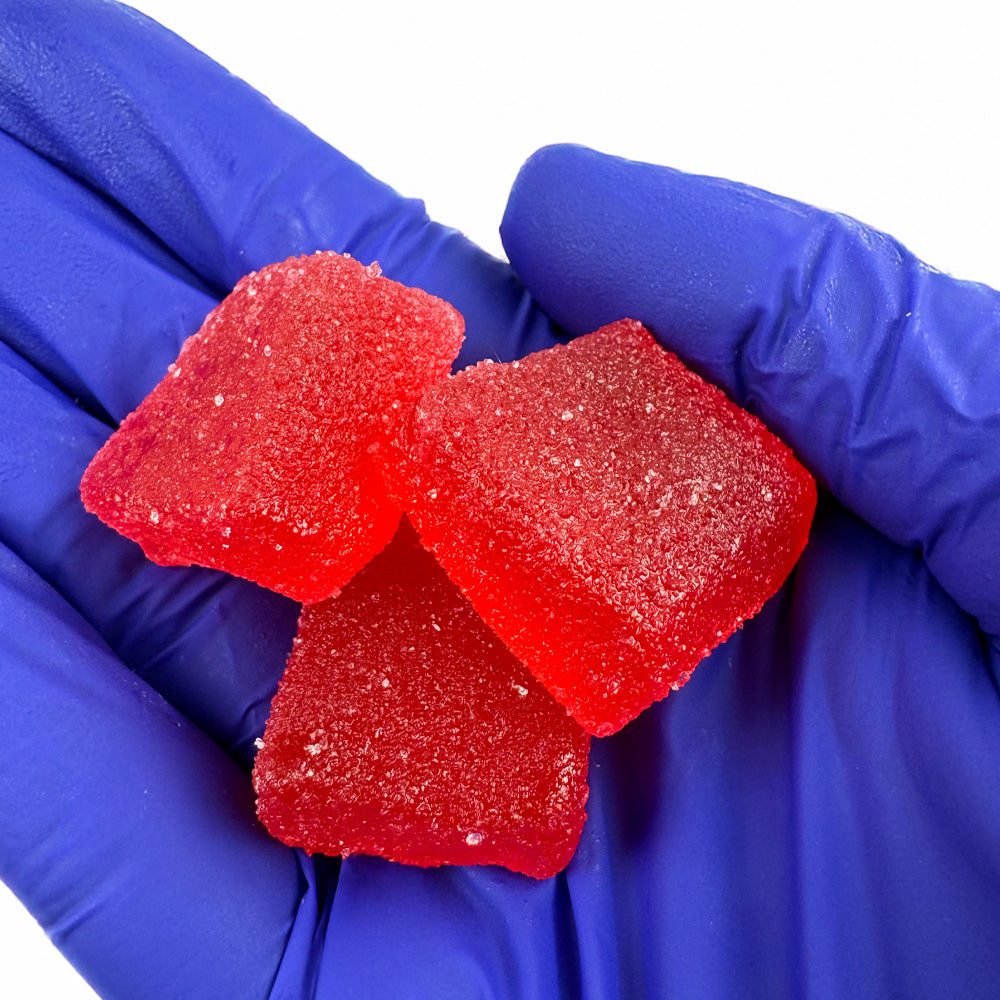 Trois gummies au THC tenus dans une main