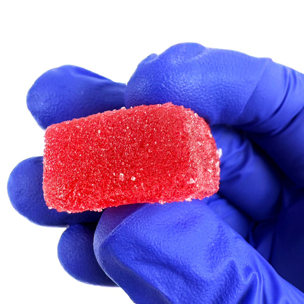 Un gummies au THC tenu dans une main